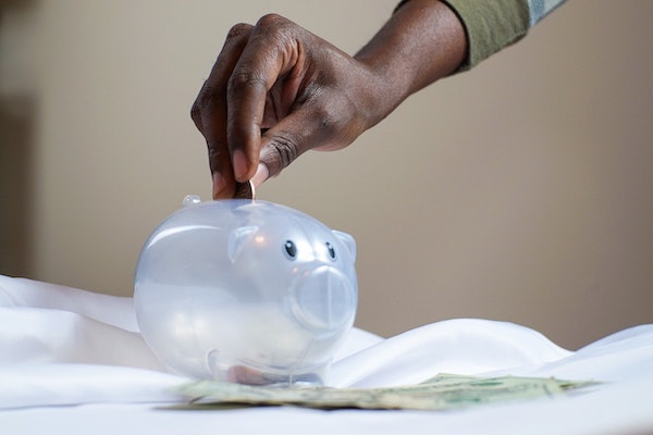 Person Putting Money into a Piggy Bank